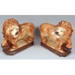 A pair of late 19thC pottery figures, of lions, each with front paw on orb, predominantly in brown