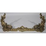 A 19thC French gilt brass fire fender, comprising two foliate rococo chenets and interlinking bar,