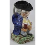 A Victorian Staffordshire Toby jug, in standing pose, the pot bellied gentleman holding jug and