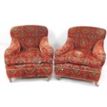 A pair of Victorian low seated easy chairs, in red patterned plush upholstery.