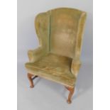 A Queen Anne walnut framed library wingback chair, upholstered in green plush material with loose