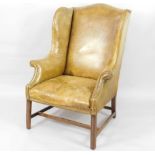 A George III mahogany framed leather upholstered wingback chair, with studded green hide and moulded