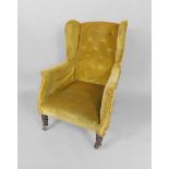 A Victorian mahogany framed wingback library armchair, upholstered in yellow fabric, raised on