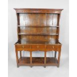 A Georgian oak and elm Welsh dresser, the outswept pediment over a two shelf Delft rack with