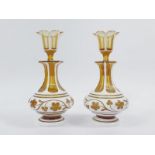 A pair of Bohemian 19thC amber and white milk flashed glass scent bottles and stoppers, of hexagonal