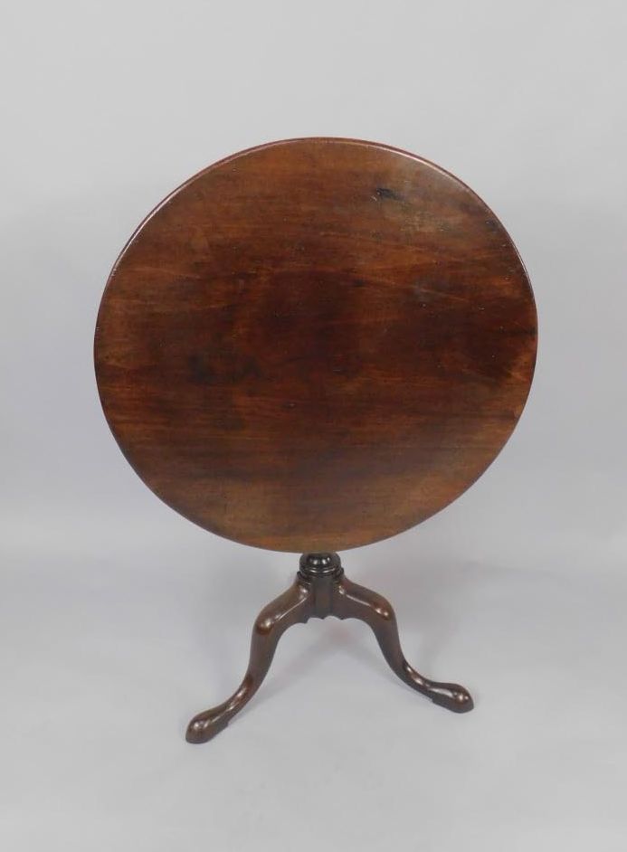 A George III mahogany tilt top occasional oval table, raised on a turned and spiral fluted column,