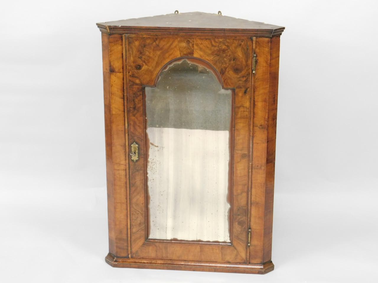 An 18thC figured walnut hanging corner cupboard, with arched mirror to the single door having