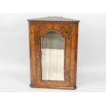 An 18thC figured walnut hanging corner cupboard, with arched mirror to the single door having