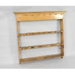 An antique graduated pine hanging plate rack, with three shelves and iron cup holders, 117cm wide.