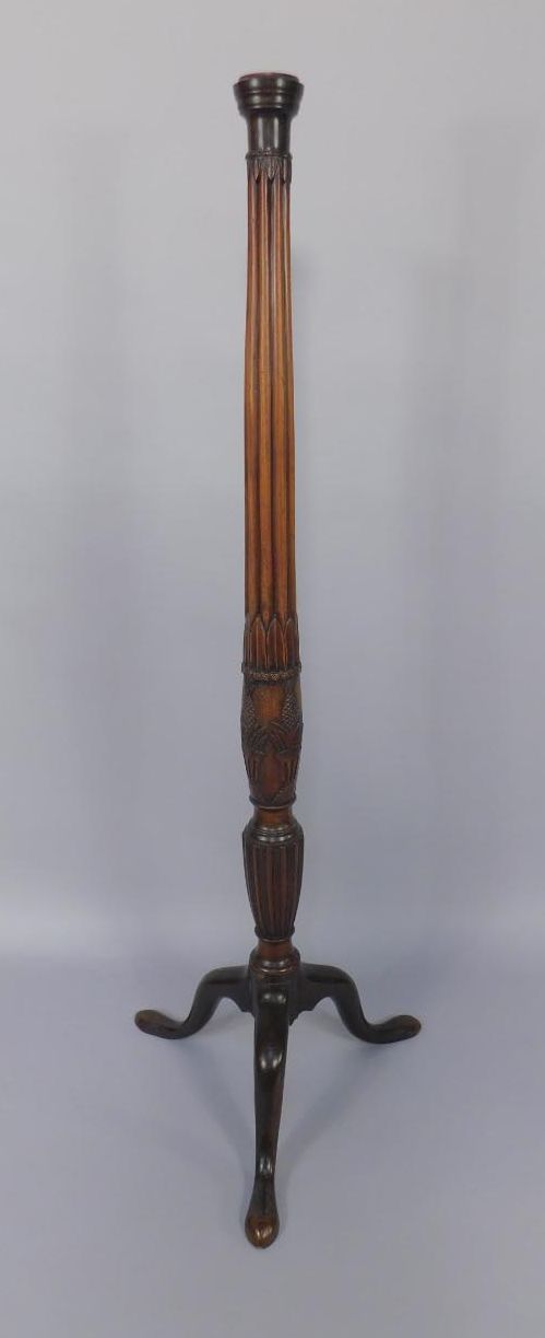 A carved mahogany bed post now converted to a floor lamp, with tripod legs.