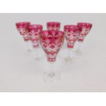 A set of six Bohemian cranberry flashed glass wine glasses, raised on fluted stems, 15cm high.