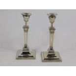 A pair of Edwardian Adam style candlesticks of urn and plinth form, on an outswept, square base,