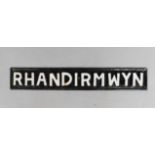 A black and white cast iron rectangular sign 'Rhandirmwyn', 9cm x 57cm.