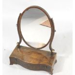 A George III mahogany dressing table mirror, the oval plate on shaped supports, the serpentine