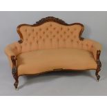 A Victorian rosewood sofa, the moulded part show-frame with a shell, flower and leaf carved crest,