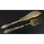 A pair of Continental white metal and plated fish servers, each with engraved decoration, the