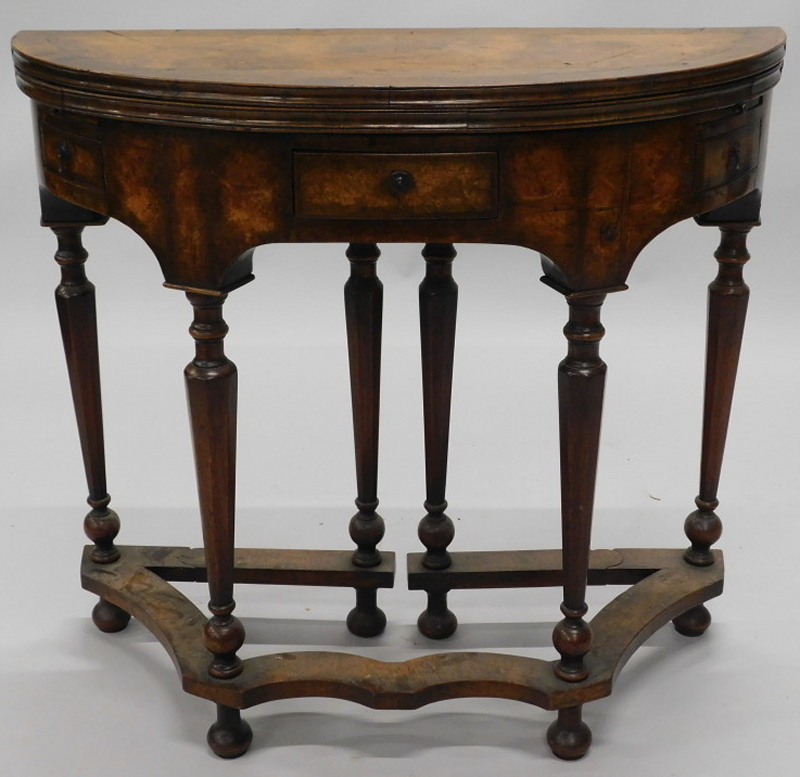 A 20thC walnut tea table in early 18thC style, the demi-lune cross and feather banded top hinged