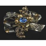 A heavy floral brooch, of bow and claw design, set with central blue paste stone, bi-colour mark