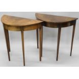 A pair of mahogany and marquetry console tables, each with a demi-lune shaped top, decorated with