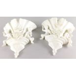 A pair of Continental porcelain wall pockets, each with a white glaze, decorated with putti etc. (