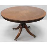 A mahogany circular dining table, with a crossbanded border on turned column and splayed leg with