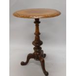 A Victorian walnut occasional table, the circular top with a carved border, on a turned column and