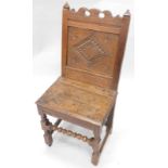 An oak side chair, the back carved with a lozenge, a solid seat, on bobbin turned central stretcher,