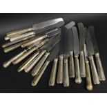 A collection of German table knives, each with a steel blade and a white metal handle, engraved with