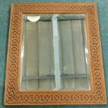 An oak wall mirror, the frame carved with a Celtic style knot and with a bevelled plate, 64cm x