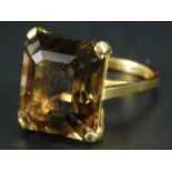 A chunky smokey quartz dress ring, with rectangular stone, in claw setting, on yellow metal band,