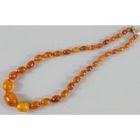 A 20thC Baltic amber style necklace, with graduated polished beads, on a cord setting, with yellow