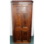 A Victorian mahogany standing corner cupboard, with four panelled doors, flanked by canted sides,