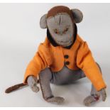 A mid 20thC felt toy monkey, wearing an orange jacket, 18cm high when seated