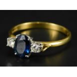 An 18ct gold sapphire and diamond dress ring, set with central oval cut sapphire, flanked by two