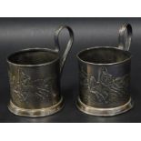 A pair of Russian silver coloured metal cup holders, each decorated with a scene with a Troika etc.,