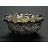 An Eastern white metal bowl, with a shaped border and decoration of elephants and other animals,