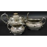 A silver plated three piece tea service, embossed with scrolls etc., the teapot lid with ivory knop