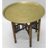 An Eastern tray table, the circular dished top engraved with writing, animals, flowers etc., the