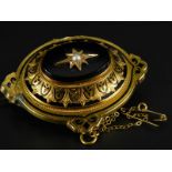 A Victorian mourning brooch, in bloom gold, with black enamel decoration, central black stone and