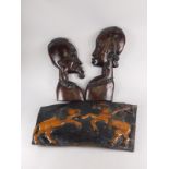 Tribal art. A pair of African style hardwood wall mounted busts, 60cm high, and a carved panel