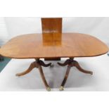 A mahogany extending two pillar dining table, in Regency style with brass paw feet, 201cm x 108cm