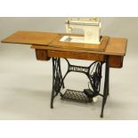 A Singer oak and iron sewing machine table, with hinged lid enclosing a later associated electric