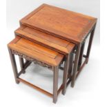 A nest of three oriental hardwood tables, each with a rectangular top and leaf and berry carved