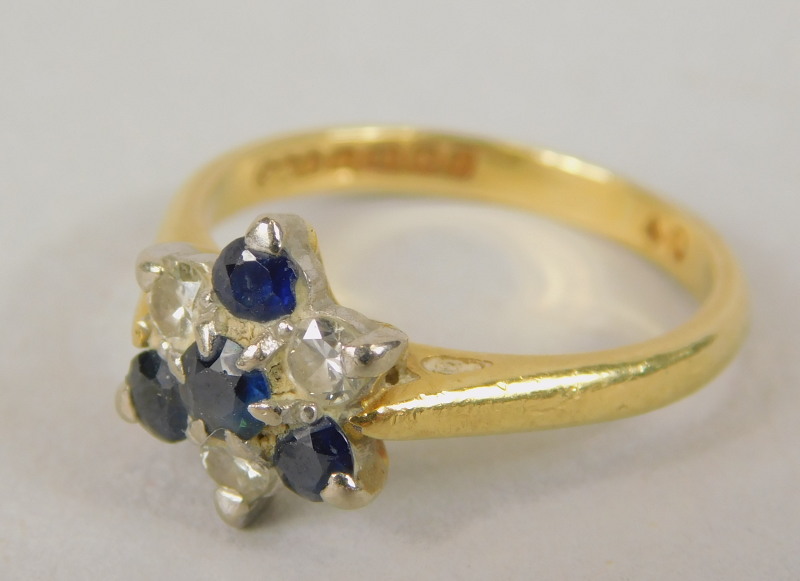 An 18ct gold dress ring, formed in floral cluster with tiny sapphire and diamonds, in the abstract