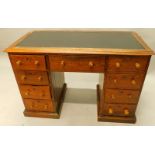 A Victorian pine kneehole desk, the top with a black leatherette inset and a panelled border,
