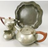 Four items of Tudric pewter, a teapot, milk jug, hot water jug and a plate with a shaped edge, (AF)