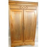 A 19thC French fruitwood armoire, with a moulded cornice, above two panelled doors, on canted