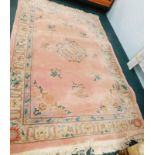 A Chinese wool carpet, with a central medallion decorated with flowers, vases etc., on a pink