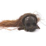 A West African type voodoo skull, with straw type and shell work head, partially bead lined to the