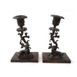 A pair of bronze candlesticks, each with shaped stems fronted by stag and hind, on rectangular